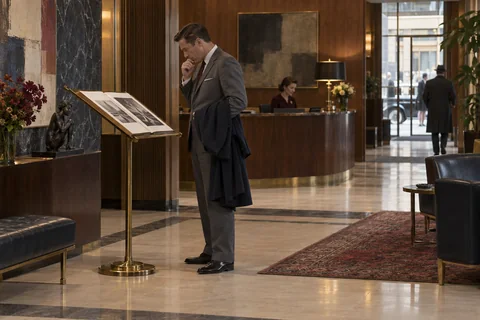 A visitor studies an open portfolio on a brass reading stand in an agency foyer.