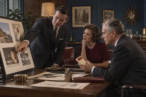 Three colleagues review photographs on a presentation board while one holds a small sample box.